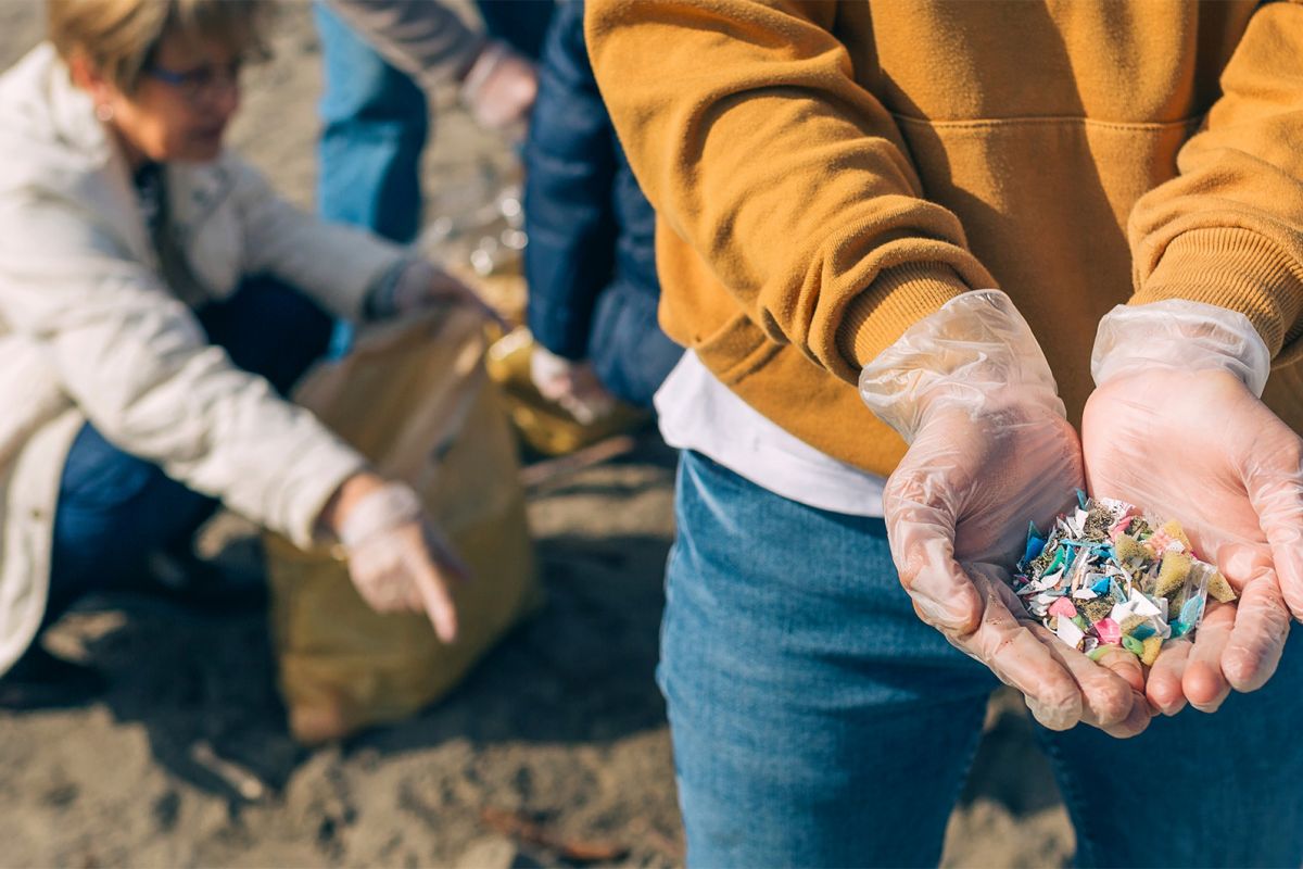 Person håller upp plastfragment på strand